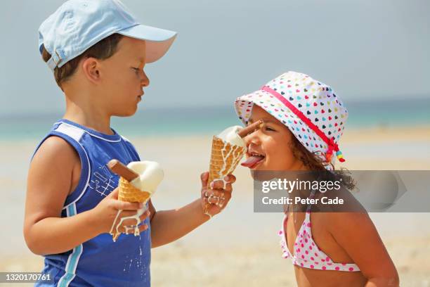 brother and sister eating melting ice creams on beach - kid eating ice cream stockfoto's en -beelden