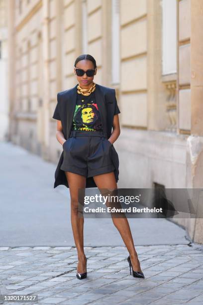 Emilie Joseph @in_fashionwetrust wears black sunglasses, silver rhinestone earrings, a bold/ chunky chain necklace from JW Anderson, a black Vintage...