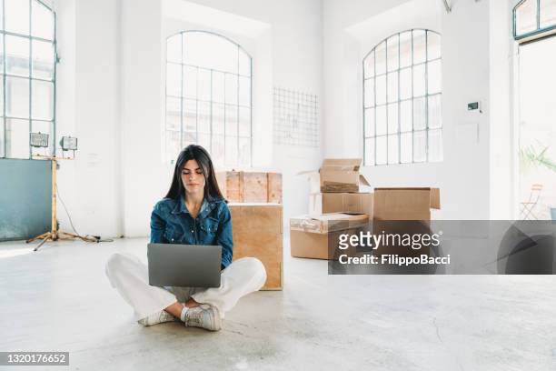 a young adult woman is working with her laptop in a new loft apartment - women wearing nothing stock pictures, royalty-free photos & images