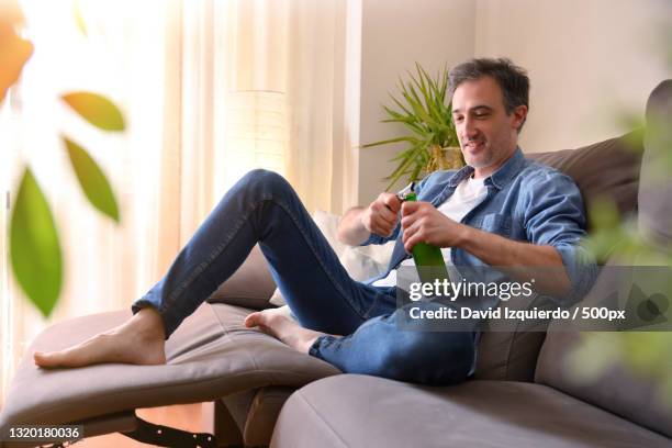 man smiling having a beer snack at home - david swallow stock pictures, royalty-free photos & images