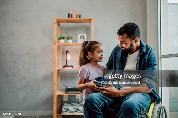 hija entrega regalo a padre en silla de ruedas - fathers day fotografías e imágenes de stock