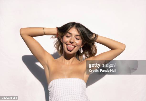 young woman with eyes closed and tongue out enjoying wellness and sun - oberkörper happy sommersprossen stock-fotos und bilder