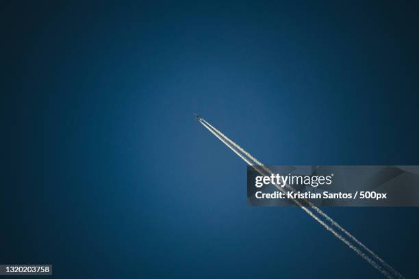 low angle view of airplane flying against clear blue sky - trace avion ciel photos et images de collection