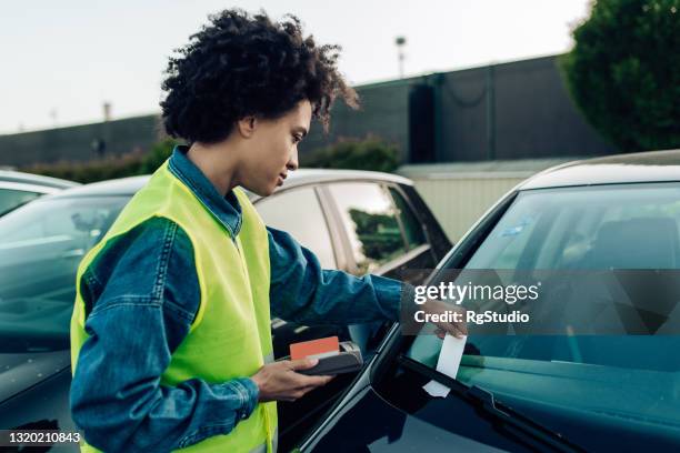 vrouw die op de parkeerplaats als parkerencontrolemechanisme werkt - verkeerspolitie stockfoto's en -beelden