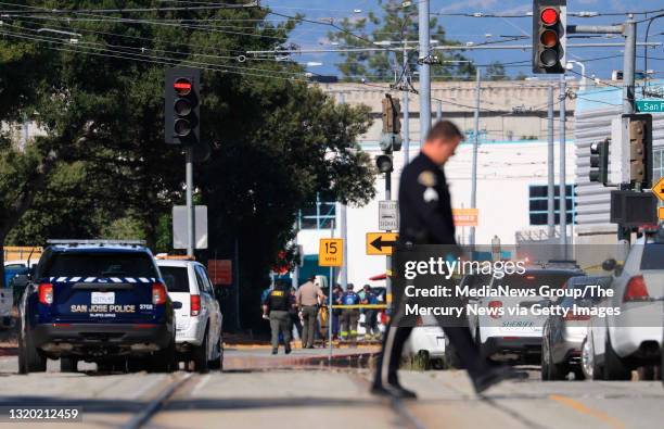 Law enforcement officer walks across Younger Avenue near the scene of a mass shooting at the VTA light rail yard in San Jose, Calif., on Wednesday,...