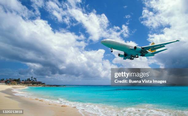 airplane flying over a beach. - maho beach stock pictures, royalty-free photos & images