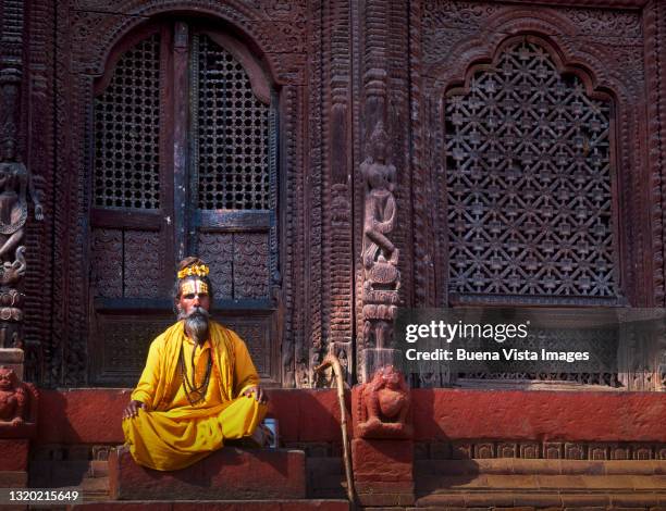 sadhu sitting on a temple's door - sadhu stock-fotos und bilder