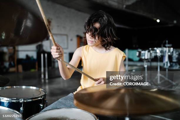 teenage drummer in tank top playing the drums looking away - children music stockfoto's en -beelden