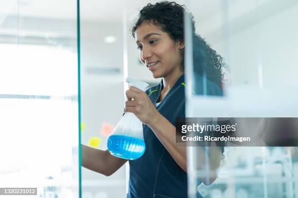 donna afro-latina pulisce le finestre di un ufficio per cui lavora - cameriera foto e immagini stock