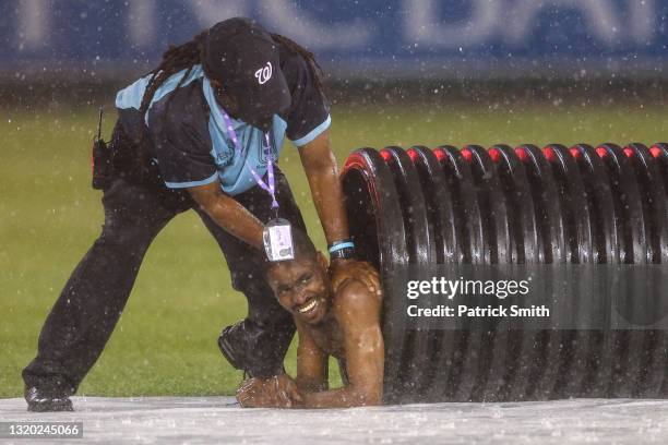 Streaker is pulled from the infield tarp roller by law enforcement and security during a rain delay between the Cincinnati Reds and against the...