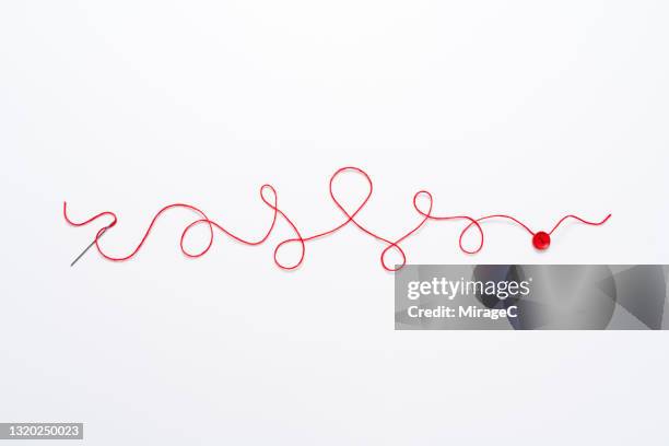 curved red thread connects needle to button - string art stock pictures, royalty-free photos & images