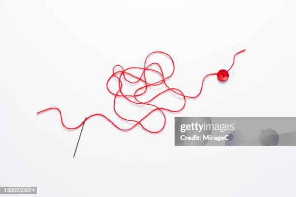 tangled red thread connects needle to button - red button stock pictures, royalty-free photos & images