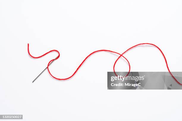 curved red thread through the sewing needle - thread sewing item stock-fotos und bilder