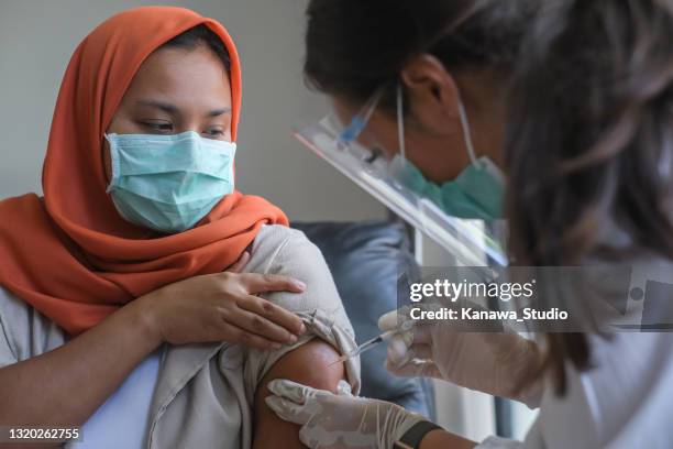 aziatische vrouwelijke arts die een patiënt het schot van vaccin geeft. - indonesische etniciteit stockfoto's en -beelden