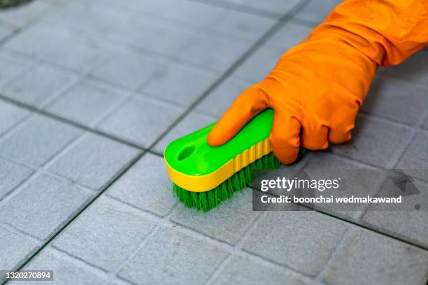 hand of man wearing orange rubber gloves is used to convert scrub cleaning on the tile floor. - luva para lavar louça imagens e fotografias de stock