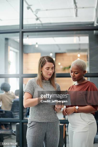 aufnahme von zwei geschäftsfrauen, die gemeinsam auf einem digitalen tablet in einem büro arbeiten - employees diversity stock-fotos und bilder
