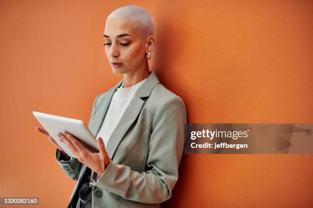 ontsproten van een jonge onderneemster die digitaal tegen een oranje achtergrond met behulp van - beauty portrait studio shot stockfoto's en -beelden