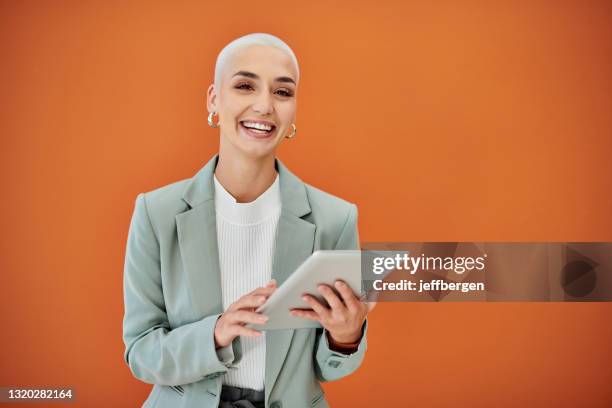 portrait of a young businesswoman using a digital against an orange background - orange blazer stock pictures, royalty-free photos & images