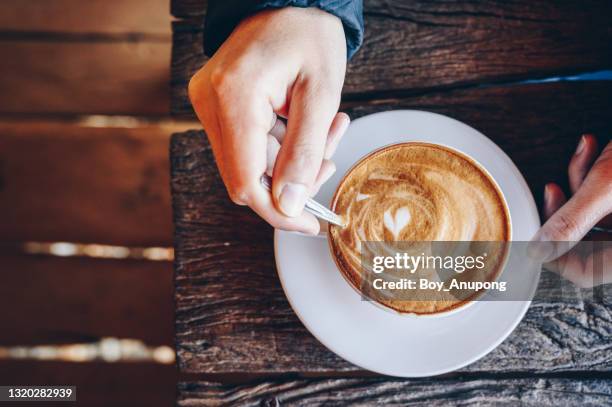 top view of person hand stirring latte coffee with spoon. - tazza di latte dall'alto foto e immagini stock