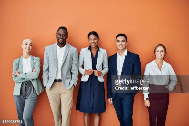portrait of a group of businesspeople standing together against an orange background - asian man white background stock pictures, royalty-free photos & images