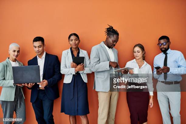porträtt av en ung affärskvinna som står bredvid sina kollegor mot en orange bakgrund - söka jobb bildbanksfoton och bilder