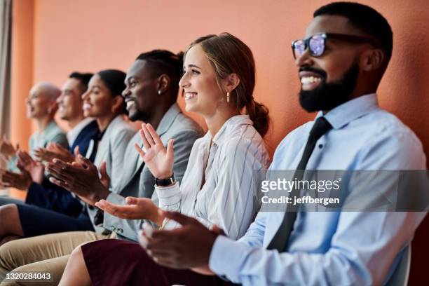 ontsproten van een groep zakenlieden die tegen een oranje achtergrond applaudisseren - business people cheering stockfoto's en -beelden