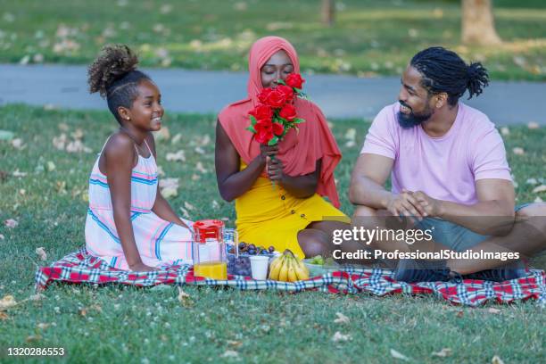 een gelukkige moslimfamilie geniet van een openluchtpicknick met fruit en bloemen. - happy arab family on travel stockfoto's en -beelden
