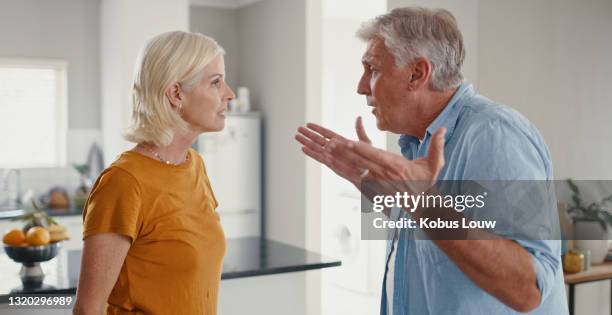 shot of a mature couple standing together at home and having an argument - an old mistress stock pictures, royalty-free photos & images