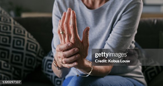 Colpo ritagliato di una donna irriconoscibile seduta da sola a casa e affette da artrite nelle sue mani Colpo ritagliato di una donna irriconoscibile seduta da sola a casa e affette da artrite nelle sue mani