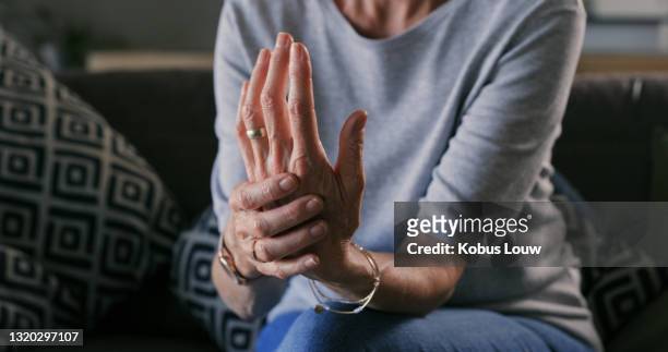 bijgesneden schot van een onherkenbare vrouw die alleen thuis zit en lijdt aan artritis in haar handen - carpaletunnelsyndroom stockfoto's en -beelden