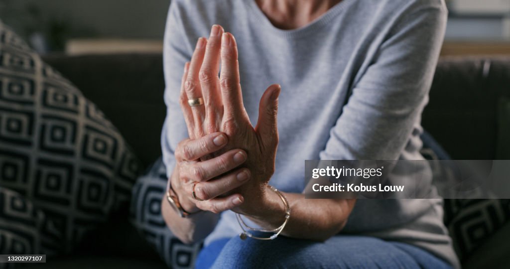 Cropped shot of an unrecognizable woman sitting alone at home and suffering from arthritis in her hands