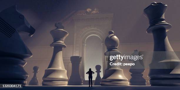 small female figure surrounded by huge chess pieces within an ornate old building - bishop chess stock pictures, royalty-free photos & images