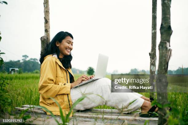 mooie vrouw die op afstand bij rijstvelden werkt - indonesia women stockfoto's en -beelden