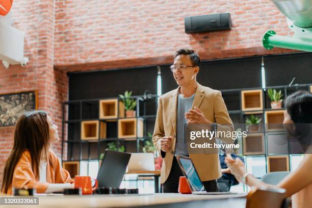 aziatische zakenman die presentatie in co-working ruimte geeft - co presented stockfoto's en -beelden