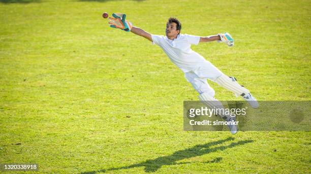wicketkeeper masculino tratando de atrapar la pelota - guardameta críquet fotografías e imágenes de stock