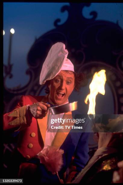 Entertainer Ken Dodd holding a frying pan above a circus fire breather, circa 1971.