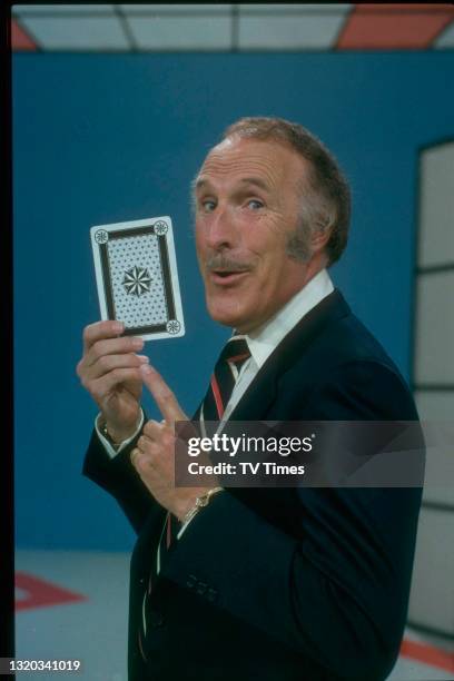 Host Bruce Forsyth holding a playing card on the set of game show Play Your Cards Right, circa 1980.