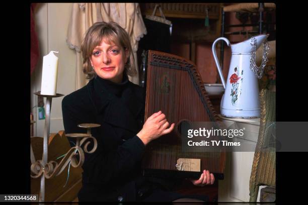 Actress Judy Flynn photographed holding an autoharp in an antique shop, circa 1997.