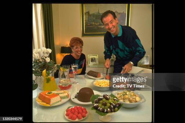 Television presenter Michael Barrymore serving dinner at home with his wife Cheryl, circa 1986.