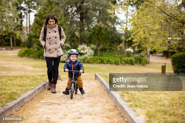 mother walking and son riding a balance bike - coimbra district stock-fotos und bilder