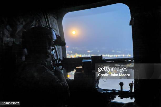 Supermoon" shines as a U.S. Army CH-47 Chinook helicopter gunner scans the desert while transporting troops on May 26, 2021 over northeastern Syria....
