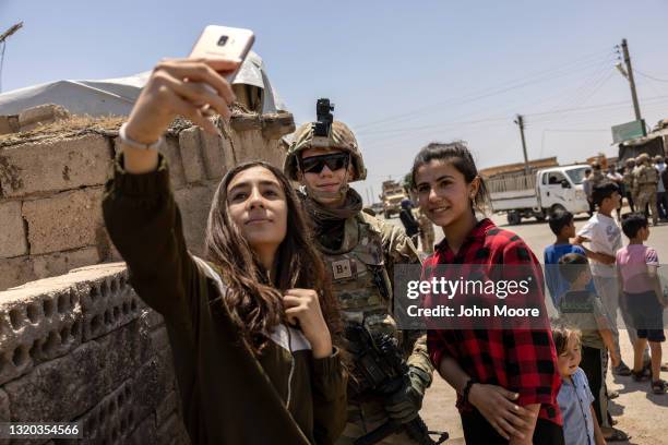 Kurdish teenagers pose for selfies with a U.S. Army soldier on joint patrol with local allies on May 25, 2021 near the Turkish border in northeastern...