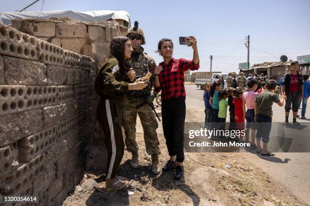 Kurdish teenagers pose for selfies with a U.S. Army soldier on joint patrol with local allies on May 25, 2021 near the Turkish border in northeastern...