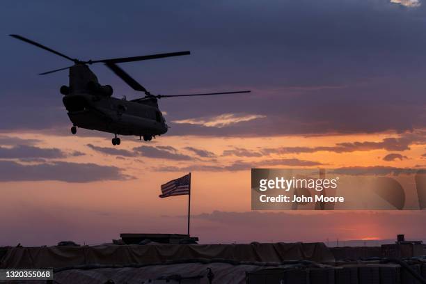 Army CH-47 Chinook helicopter takes off at sunset while transporting American troops out of a remote combat outpost known as RLZ on May 25, 2021 near...