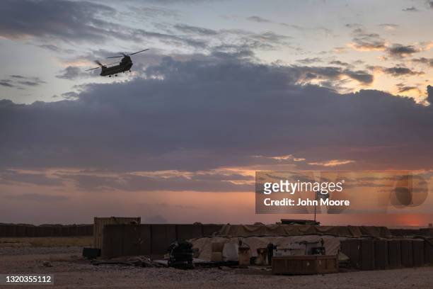 Army CH-47 Chinook helicopter takes off at sunset while transporting American troops out of a remote combat outpost known as RLZ on May 25, 2021 near...
