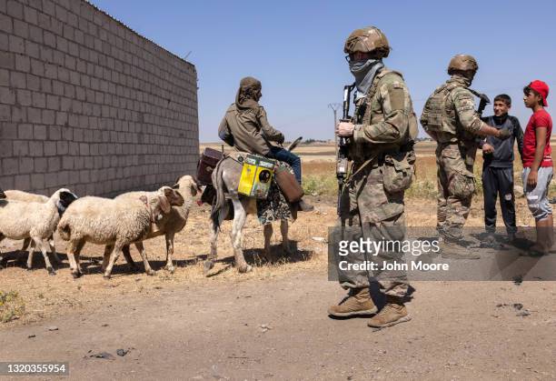 Sheepherder and his flock pass U.S. Army soldiers on patrol on May 26, 2021 near the Turkish border in northeastern Syria. U.S. Forces, part of Task...