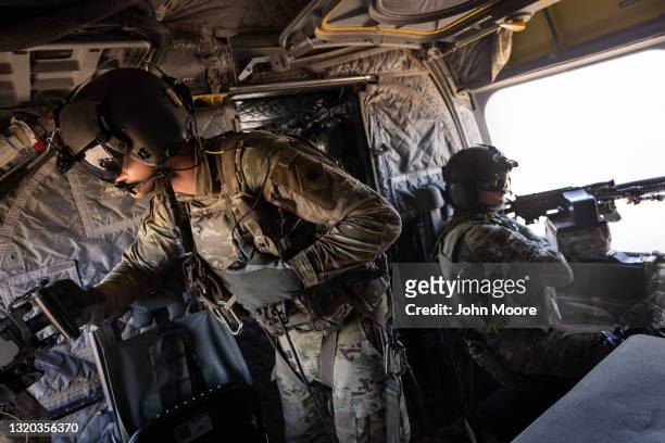 Army CH-47 Chinook helicopter gunners scan the desert while transporting troops on May 26, 2021 over northeastern Syria. U.S. Forces, part of Task...