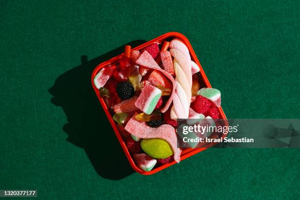 top view of a red plastic box filled with gummy candies on a green background. - confectioner stock pictures, royalty-free photos & images