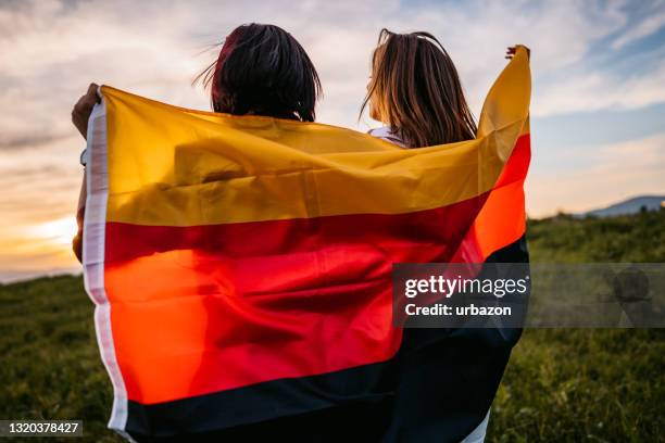 兩個女人在草地上用德國國旗遮蓋自己 - german flag 個照片及圖片檔