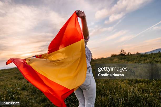 femme répandant le large indicateur espagnol au coucher du soleil - drapeau espagnol photos et images de collection